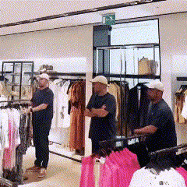 two men are standing in a clothing store with a green exit sign above them