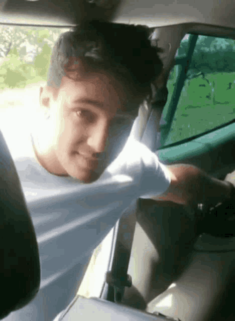 a young man is sitting in the back seat of a car with his shirt pulled up