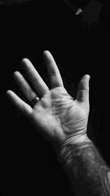 a black and white photo of a man 's hand with a ring on it