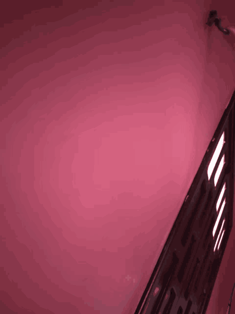 a pink wall with a black railing and a few lights on it