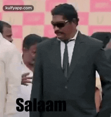 a man in a suit and tie is standing in a crowd of people and says salaam .