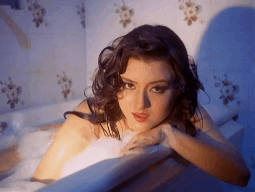 a woman is taking a bath in a bathtub filled with soap bubbles .