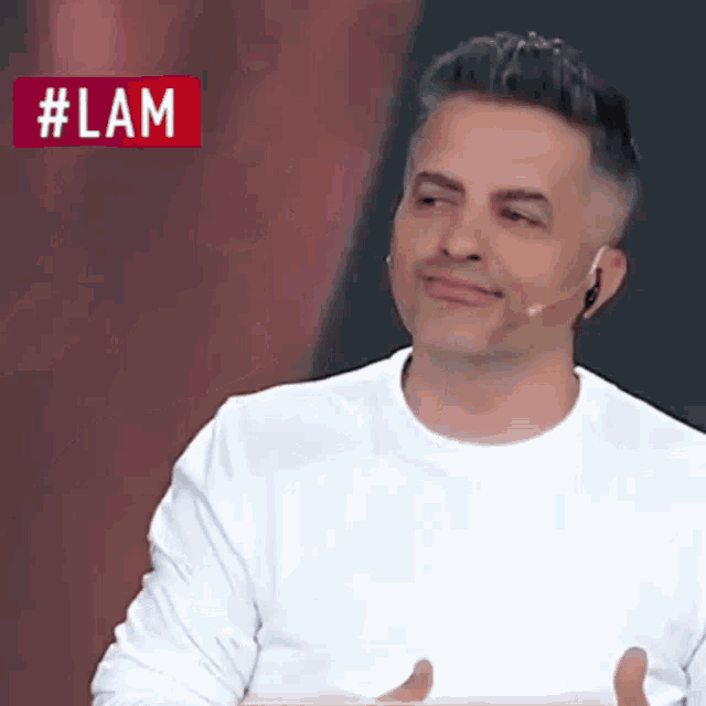 a man wearing a white shirt and a microphone with the hashtag #lam