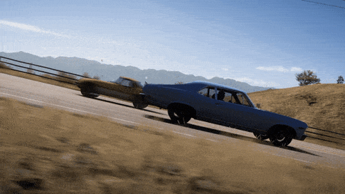 a blue car is driving down a road next to another car