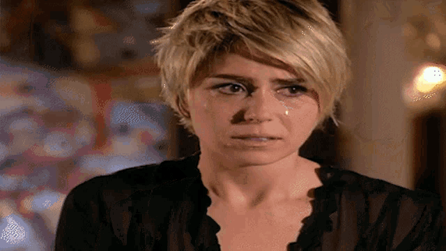 a woman with short blonde hair is crying with a tear running down her cheek