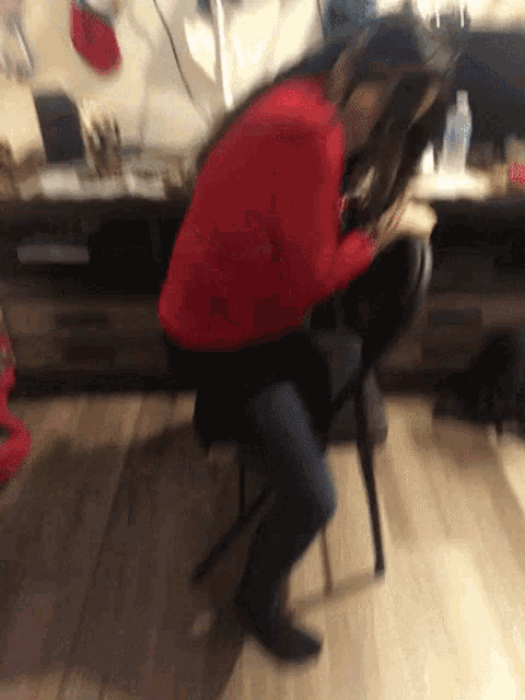 a woman in a red sweater sits on a black chair