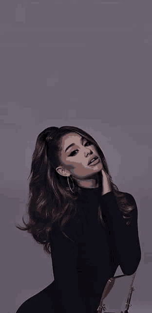 ariana grande is wearing a black turtleneck and earrings while sitting in front of a mirror .