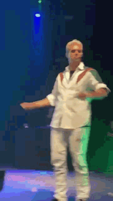 a man in a white shirt dancing on a stage