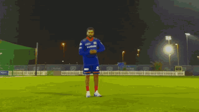 a man wearing a blue samsung jersey stands on a field