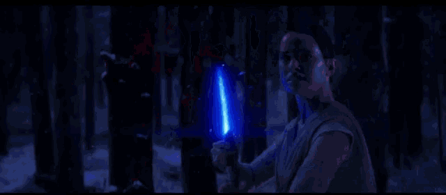 a person holding a red light saber in a dark forest