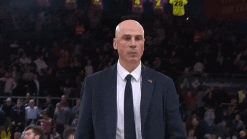 a man in a suit and tie is walking in a dark room