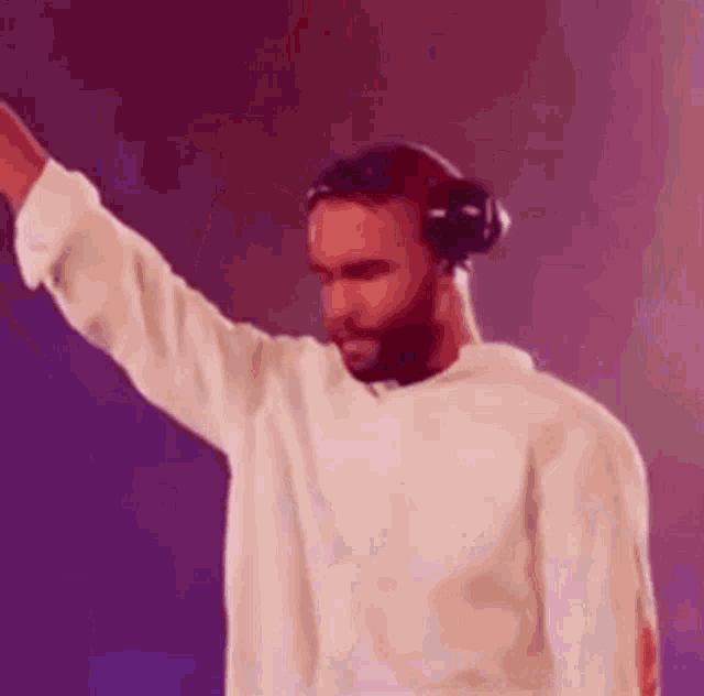 a man wearing headphones and a white sweater is dancing .