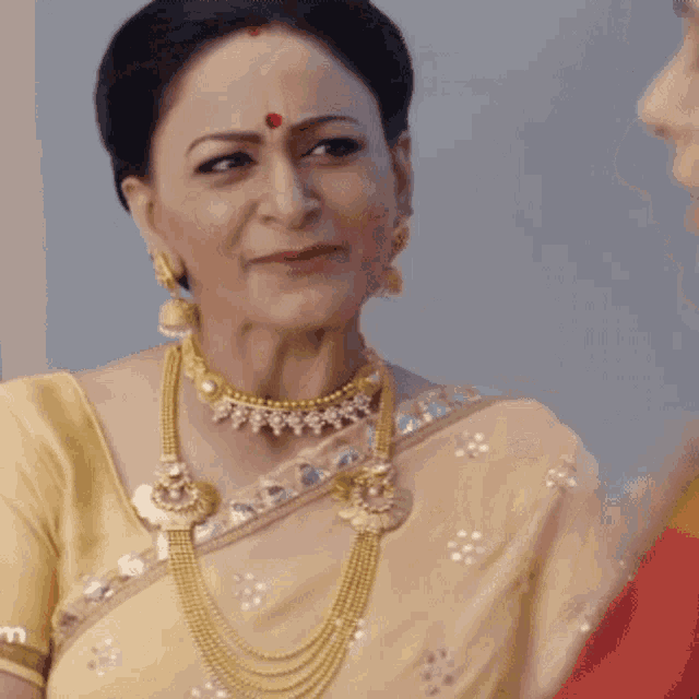 a woman with a red dot on her forehead is wearing a gold necklace and earrings