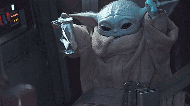 a baby yoda is holding a bag of food