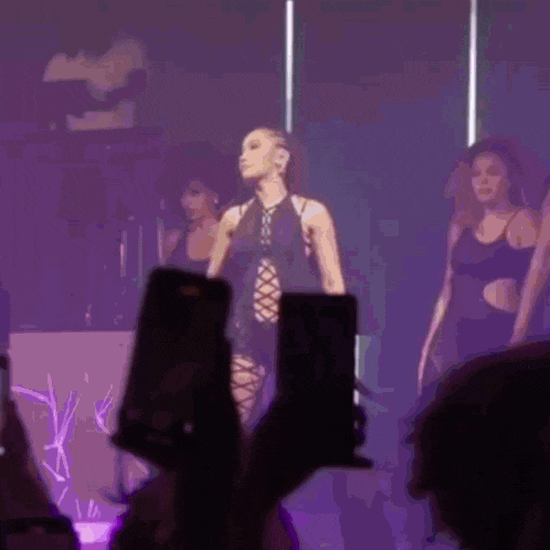 a woman in a lace up top is being photographed by a crowd at a concert .