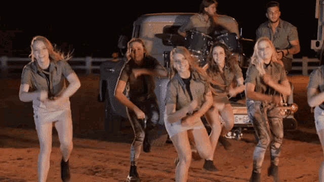 a group of people are dancing in front of a van that says g4df on the back
