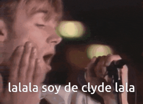 a man singing into a microphone with the words " lalala soy de clyde lala " above him