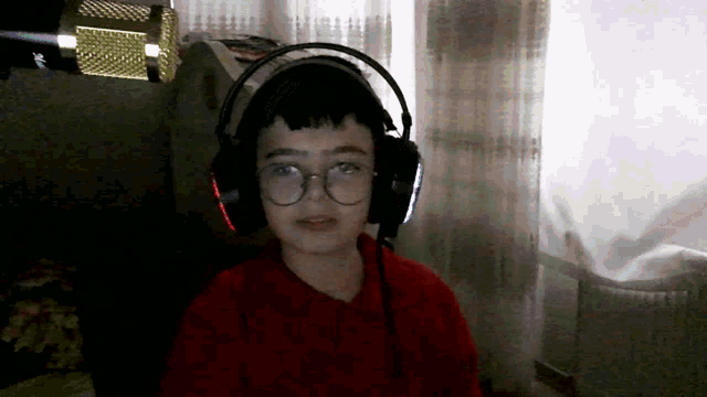 a young boy wearing headphones and glasses is looking at the camera