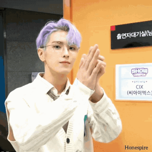 a young man with purple hair stands in front of a sign that says show