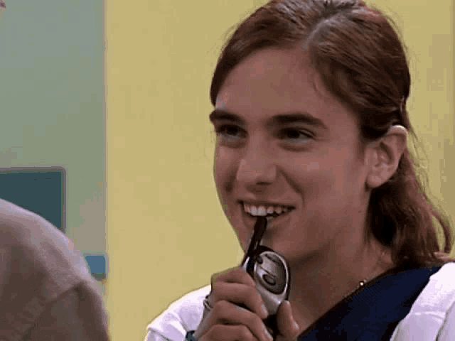 a woman is smiling while holding a cell phone with the number 6 on it