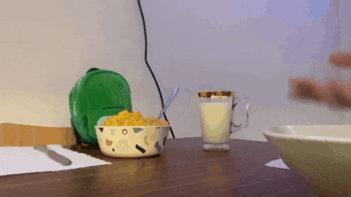 a bowl of cereal and a glass of milk on a table
