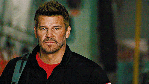 a man with a beard is wearing a red shirt and a black jacket