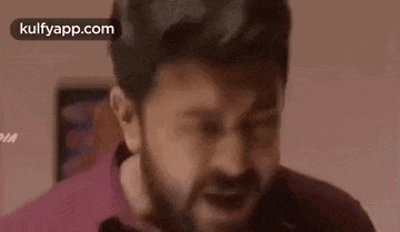 a man with a beard is making a funny face with his mouth open in a room .