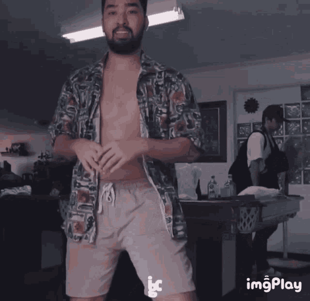 a shirtless man is dancing in front of a wall with images on it and the word imgplay on the bottom
