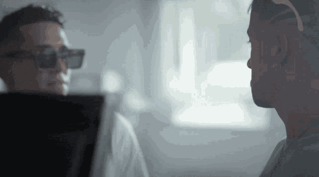 a man wearing sunglasses talks to another man in a room