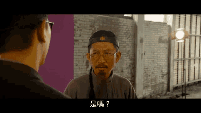 a man wearing glasses and a hat talks to another man in chinese