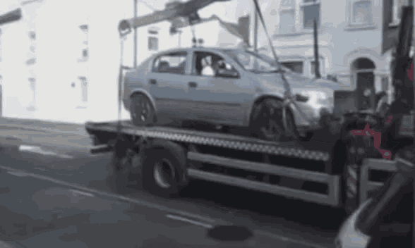 a car is being towed by a tow truck on a street