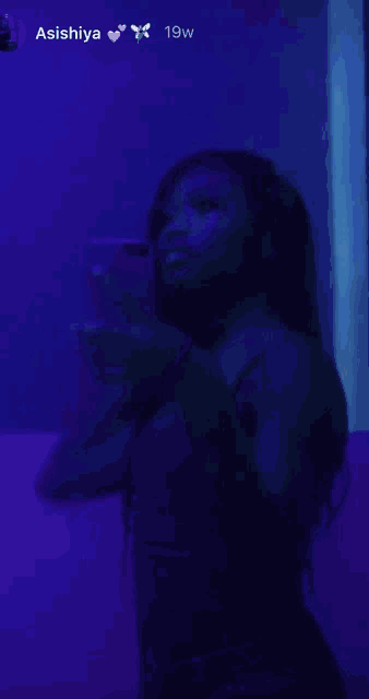 a woman is taking a selfie in front of a mirror with a purple background .