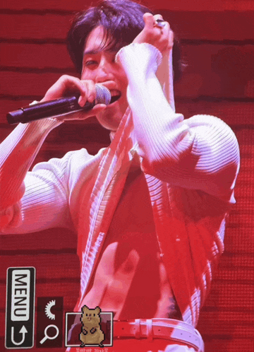 a man is singing into a microphone with a menu arrow pointing to the right