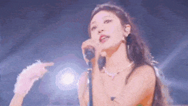 a woman is singing into a microphone on a stage in front of a crowd .