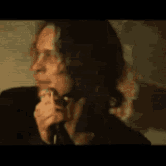 a man is singing into a microphone with his mouth open and smoking a cigarette .