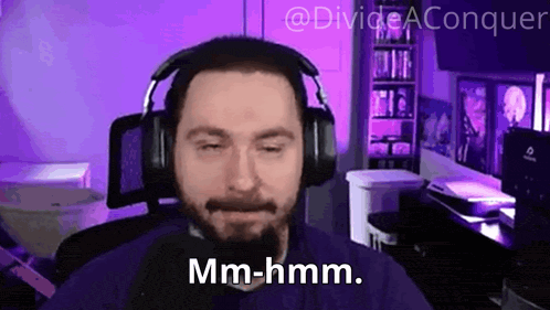 a man wearing headphones is sitting in front of a purple background and says mm-hmm .