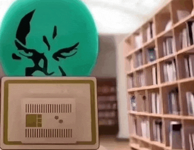 a green balloon with a face on it is sitting on top of a laptop in a library .