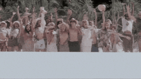 a large group of people are standing on a beach with their arms in the air