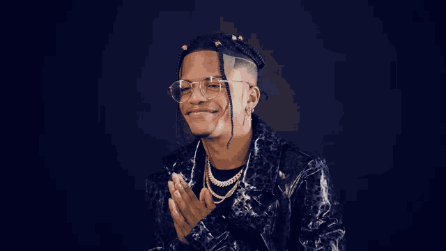 a man wearing glasses and a leopard print jacket is clapping his hands
