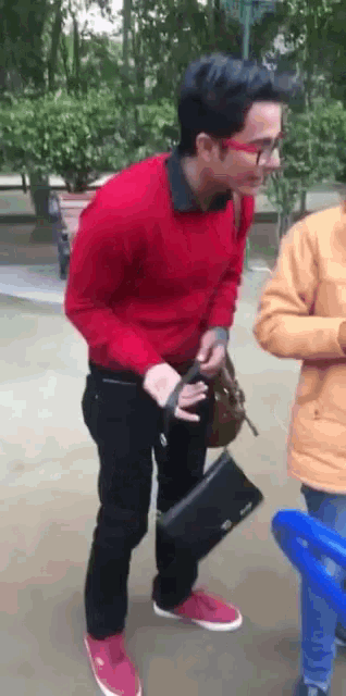 a man in a red sweater and red shoes is holding a black purse