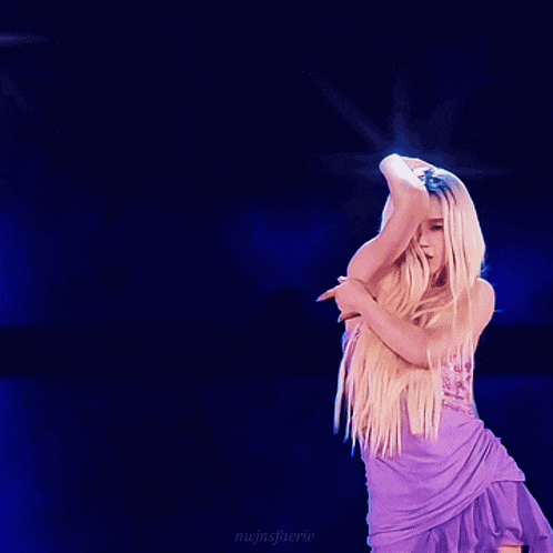 a woman in a purple dress is dancing in front of a blue background