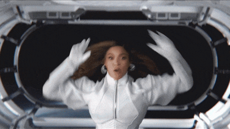 a woman in a white jacket and white gloves is standing in a dark room