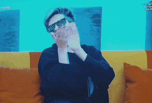 a man wearing sunglasses is sitting on a couch with the word tokyo on the wall