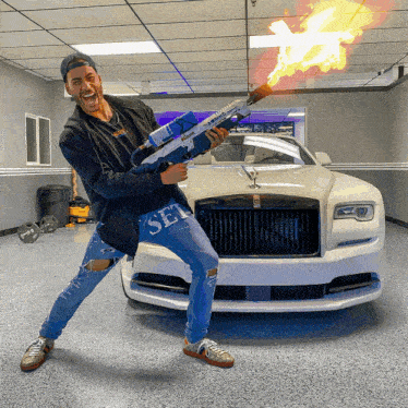 a man is holding a gun in front of a rolls royce car