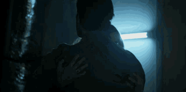a man and a woman hugging in a dark room