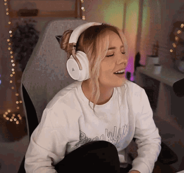 a woman wearing headphones and a sweatshirt that says brooklyn is smiling
