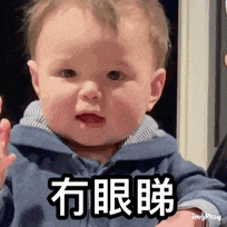 a baby in a blue jacket is making a funny face and waving .