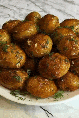a white plate topped with fried potatoes with dill and garlic .