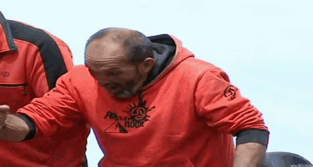 a man wearing a red sweatshirt with the word rock on it looks down