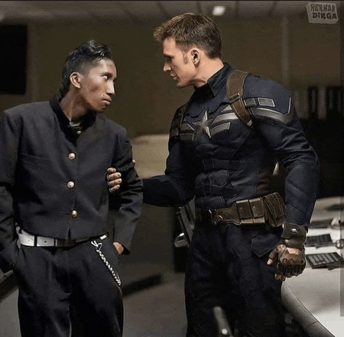 a man in a captain america uniform talks to another man in a black suit